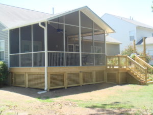 Exterior view of home with wooden stairs leading to screen enclosure.