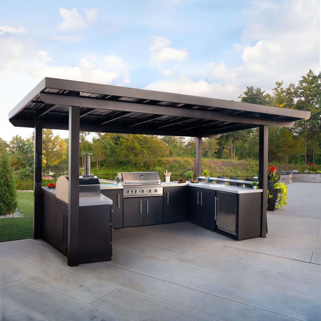 Modern linear outdoor kitchen with a large stainless steel grill, integrated pizza oven, and black storage cabinets on a concrete patio.