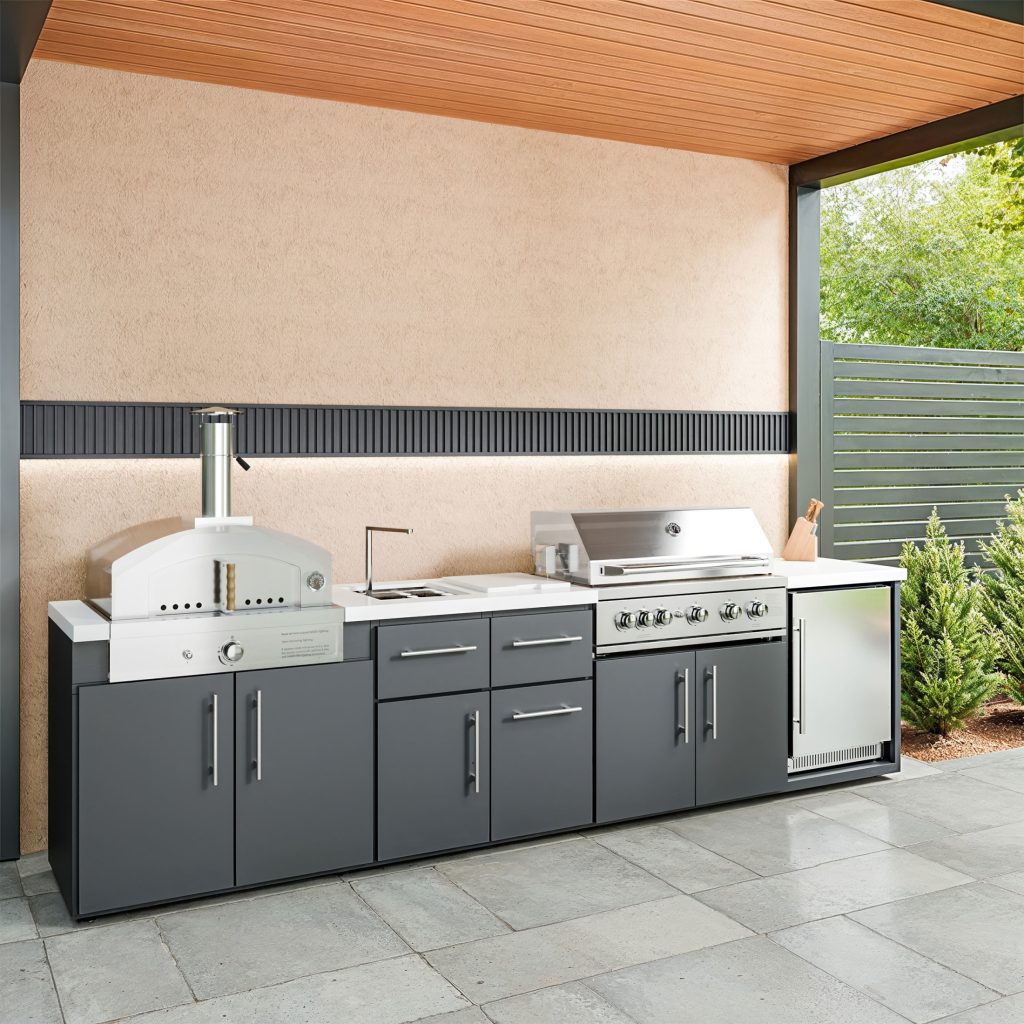 Emory 12-foot linear outdoor kitchen featuring a stainless steel pizza oven, gas grill, and built-in fridge with dark grey cabinetry.