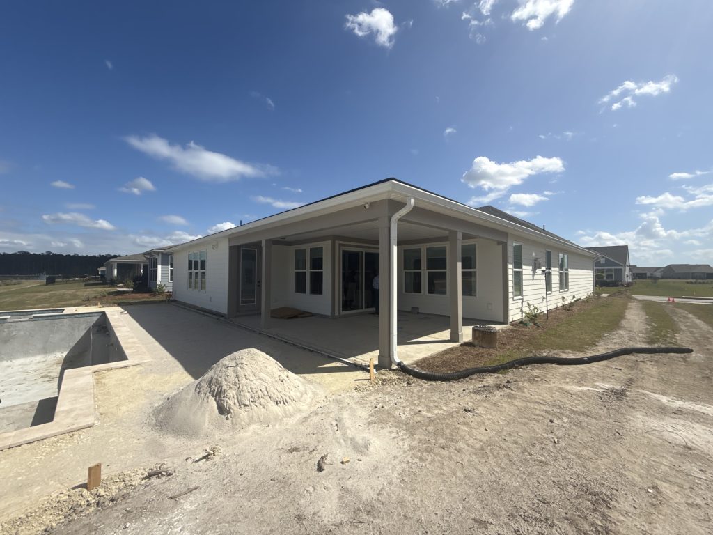 Pre-construction view of a backyard in Del Webb Nexton. We are prepping the site for a custom screen enclosure and a travertine paver patio adjacent to the pool.