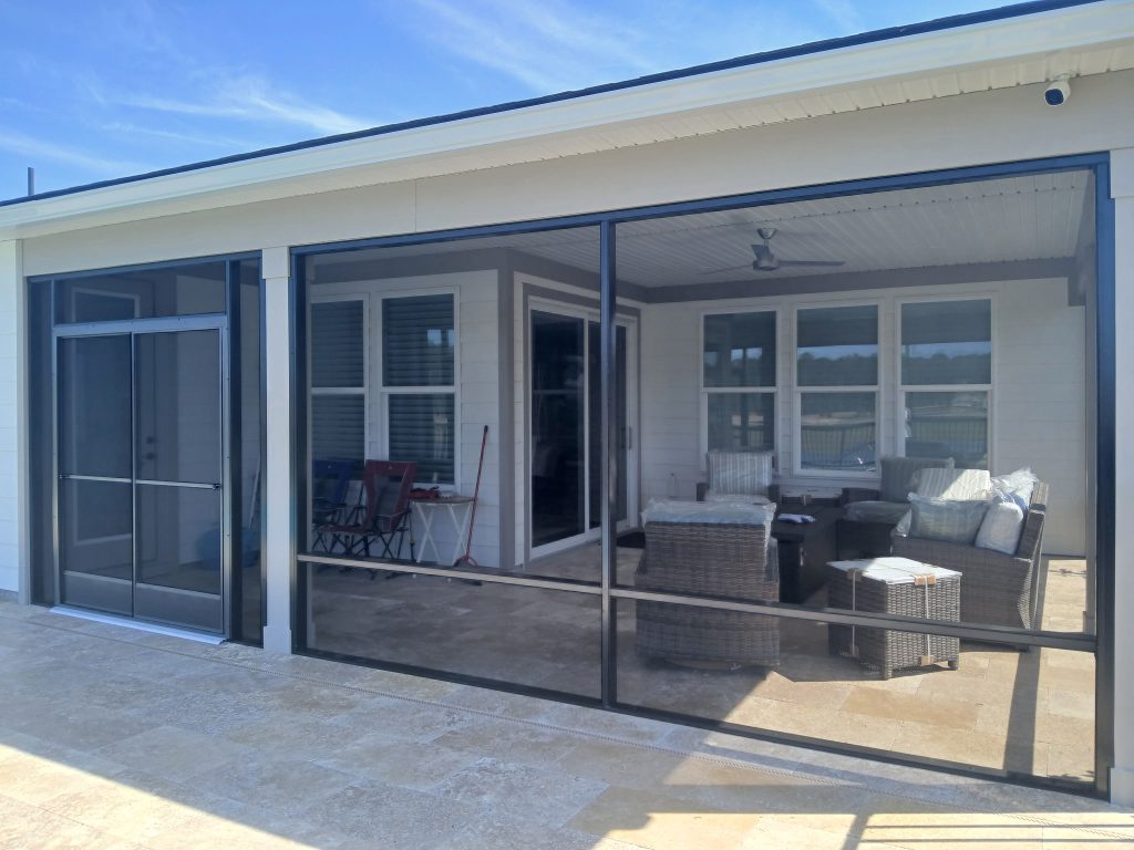 The finished results! A custom-engineered screen enclosure integrates seamlessly with the existing home in Summerville, featuring premium travertine pavers that transition beautifully to the new pool deck.
